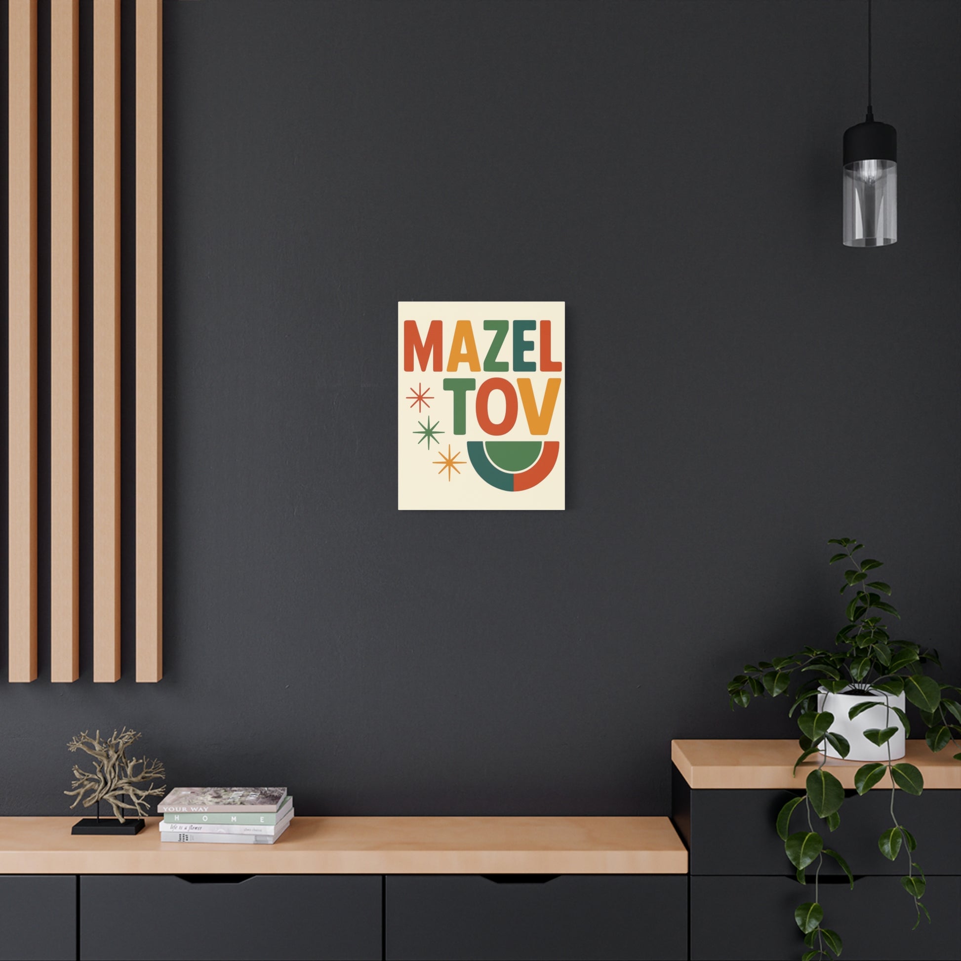 Colorful 'Mazel Tov' poster on a dark wall with wooden shelves and plants.