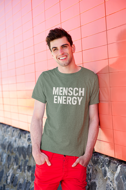 Man wearing a green t-shirt with 'MENSCH ENERGY' text against a pink tiled wall.
