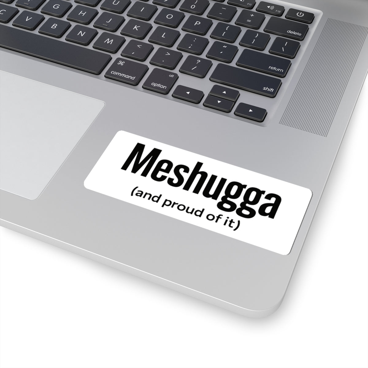 Laptop with a sticker reading 'Meshugga (and proud of it)' on a white background