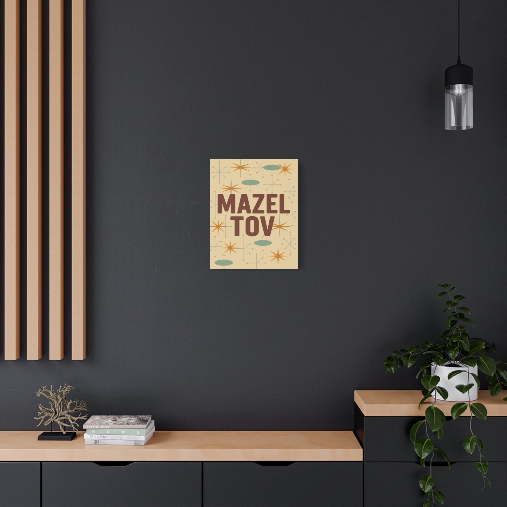 Poster with 'Mazel Tov' text on a dark wall above a wooden shelf.