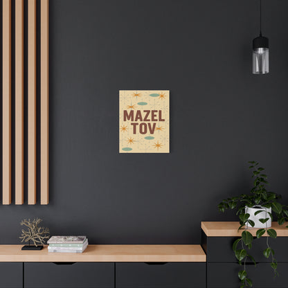 Poster with 'Mazel Tov' text on a dark wall above a wooden shelf.