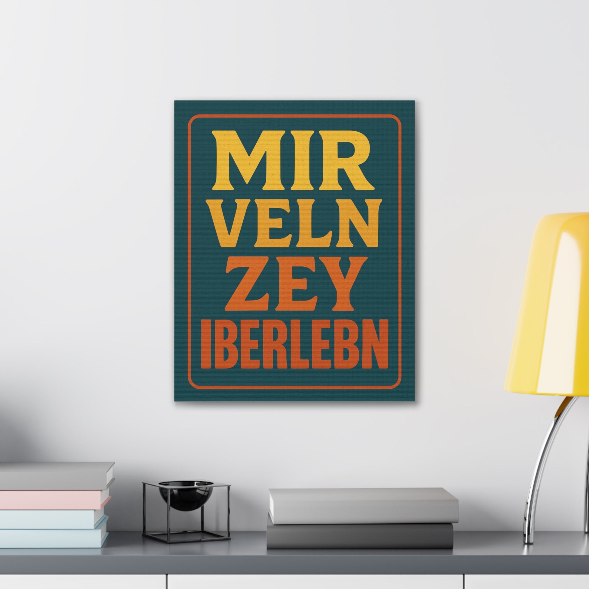 Framed artwork with text on a wall above a desk with books and a lamp.