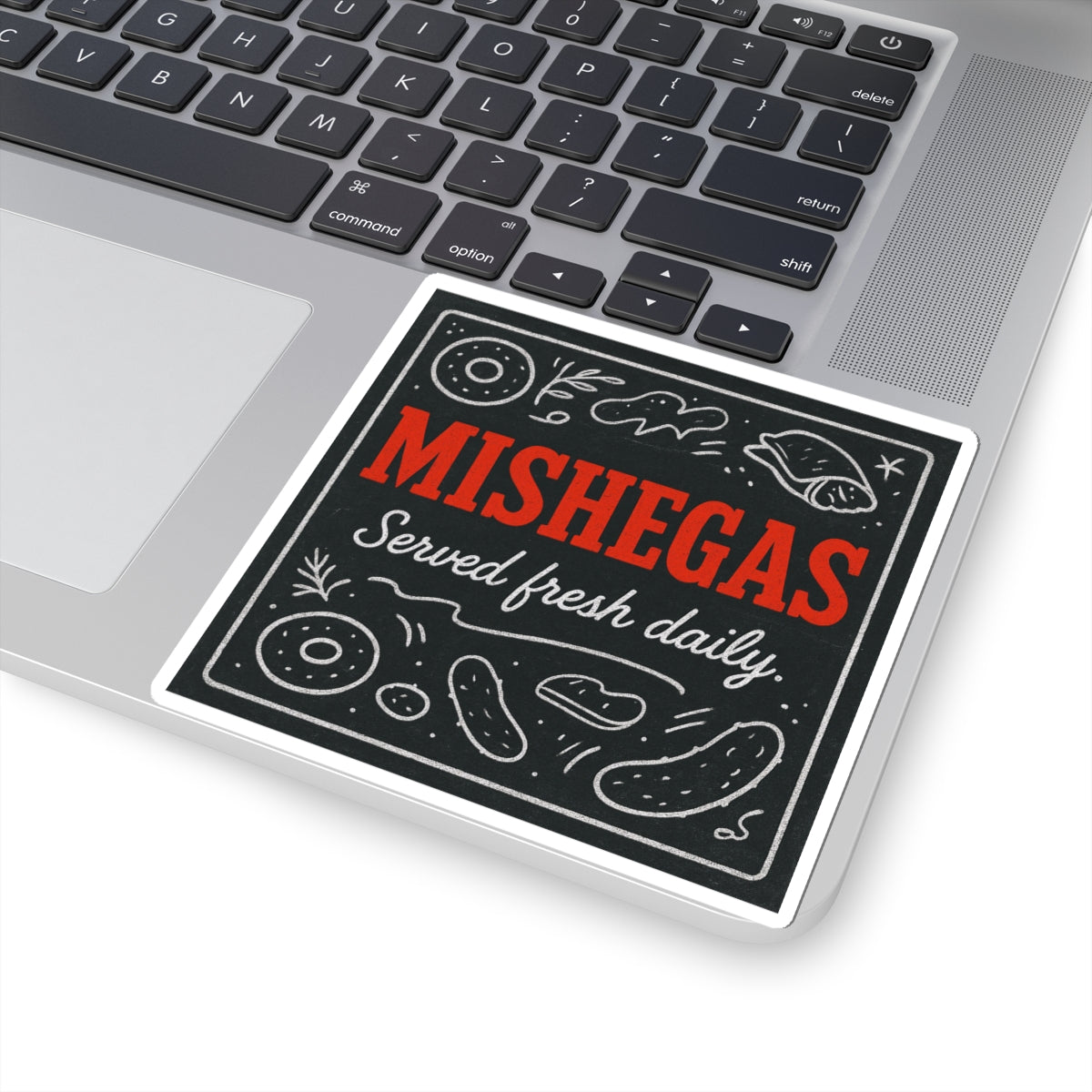 Sticker with 'MISHEGAS Served fresh daily' text on a laptop