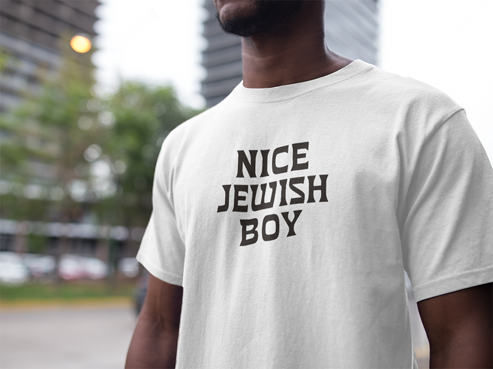 Person wearing a white t-shirt with 'Nice Jewish Boy' text in an urban setting