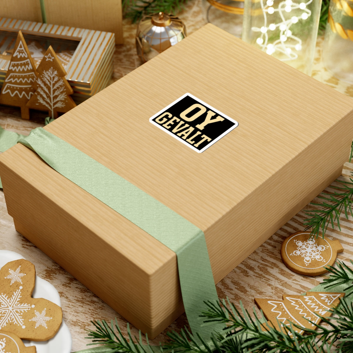 Wooden gift box with a green ribbon and 'OY GEVALT' label, surrounded by Christmas decorations.