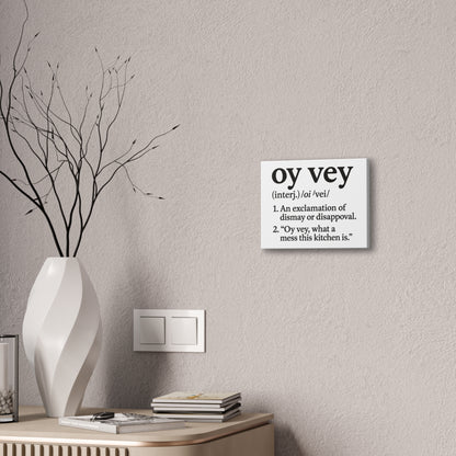 Decorative wall sign with 'oy vey' definition on a neutral wall with a vase and books.