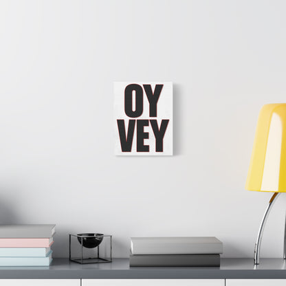 Decorative wall art with 'OY Vey' text on a white wall above a shelf with books and a lamp.