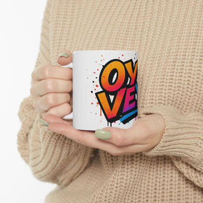 Person holding a mug with colorful 'oy vey' design against a neutral background