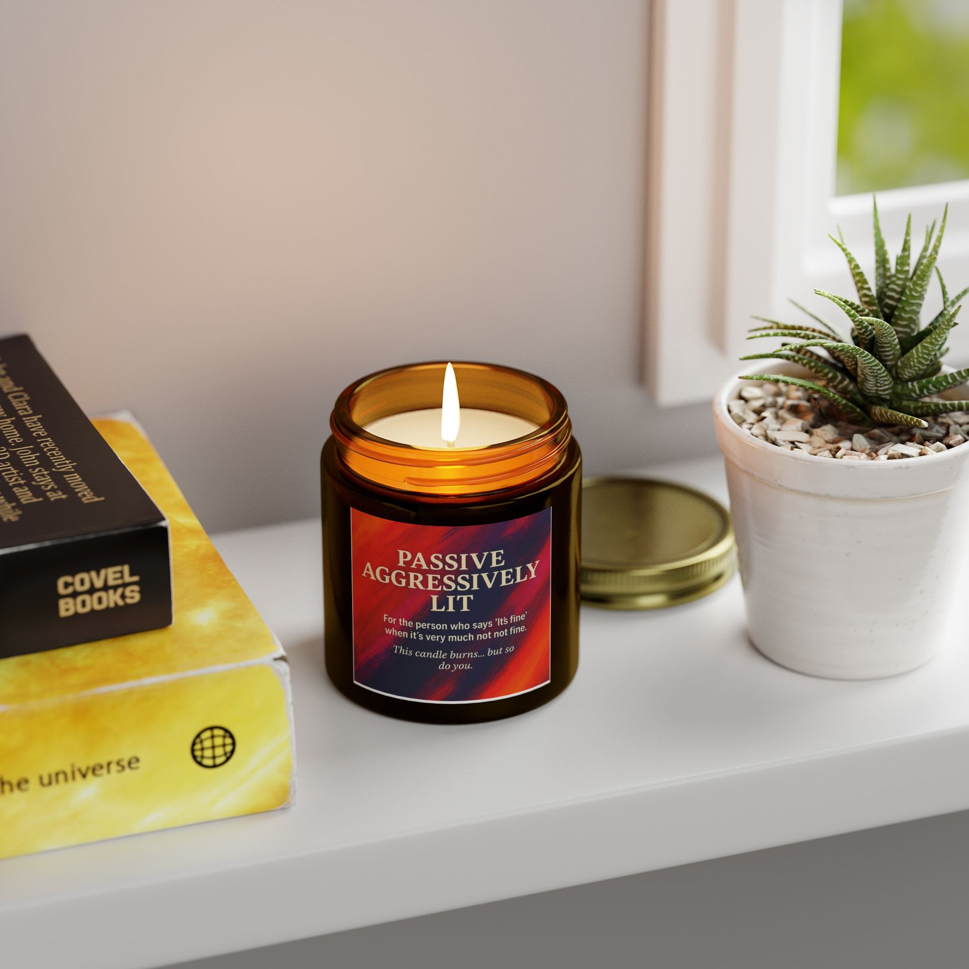 Candle with a humorous label on a shelf next to books and a plant