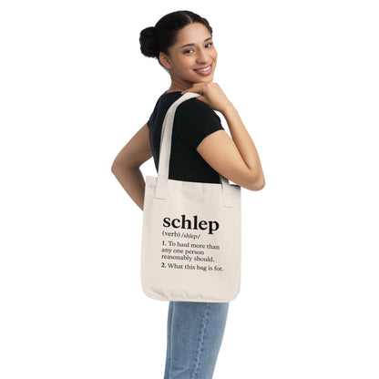 Woman holding a tote bag with the word 'Schlep' printed on it against a white background