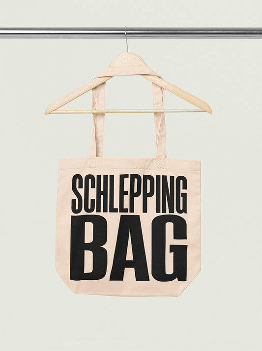 Tote bag with 'SCHLEPPING BAG' text on a hanger against a light background