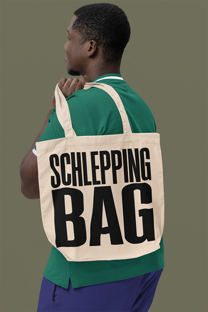 Man carrying a tote bag with 'SCHLEPPING BAG' text on a plain background