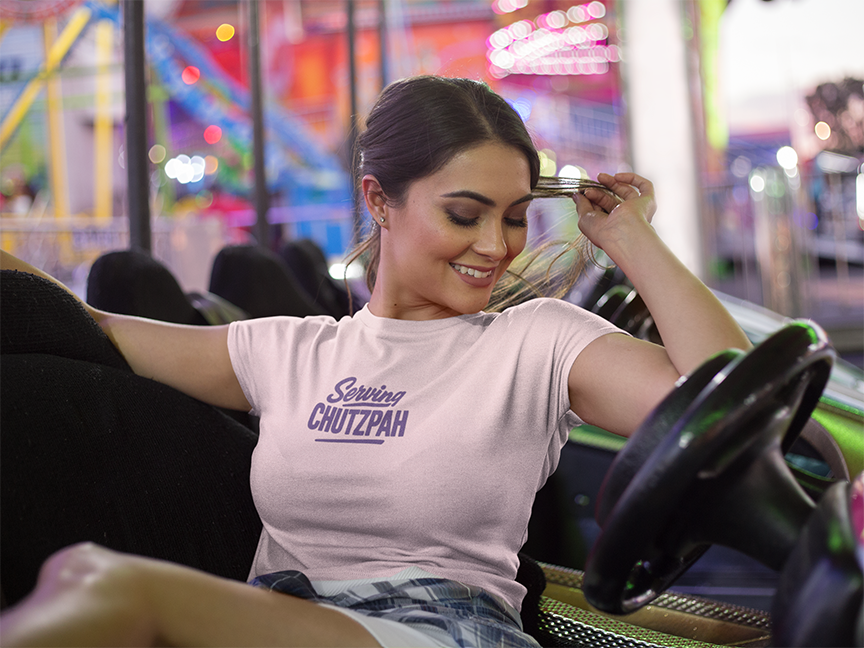 Woman in a pink 'serving chutzpah' t-shirt with text on an amusement park ride