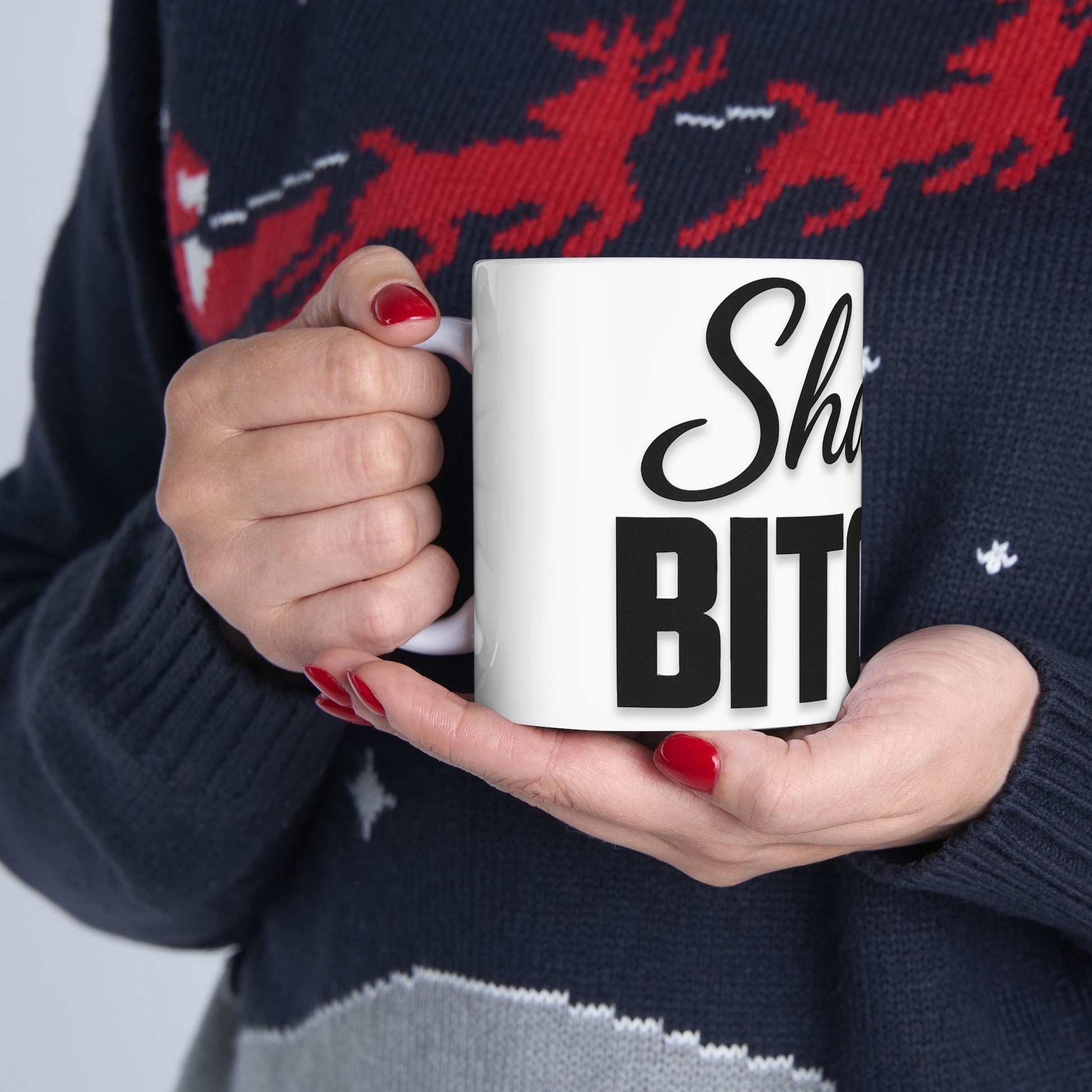 Person holding a mug with 'Shalom Bitches' text against a patterned sweater background