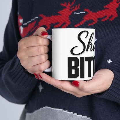 Person holding a mug with 'Shalom Bitches' text against a patterned sweater background