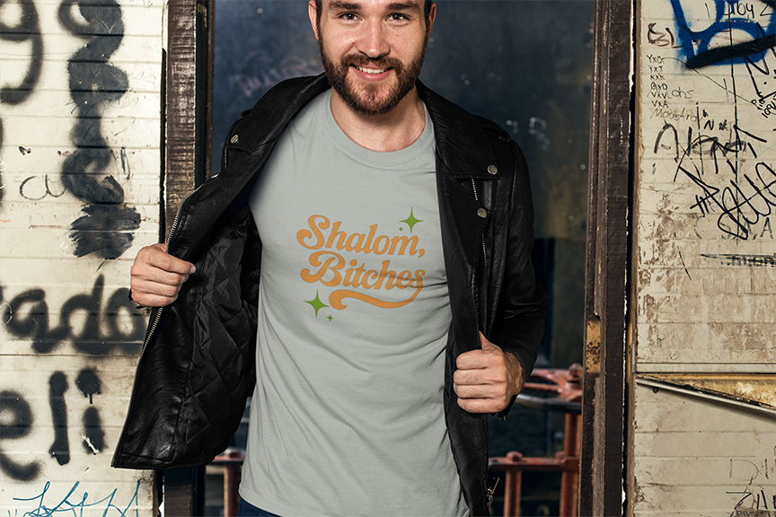 Man wearing a t-shirt with 'Shalom Bitches' text in an urban setting