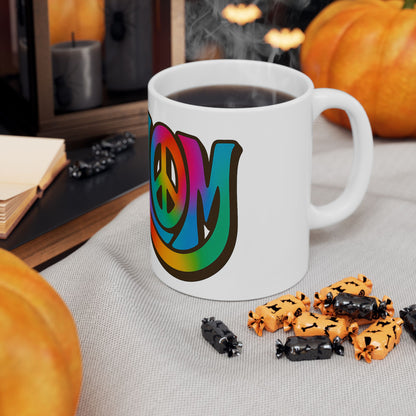 White mug with colorful 'shalom' design on a table with Halloween-themed treats and pumpkins.