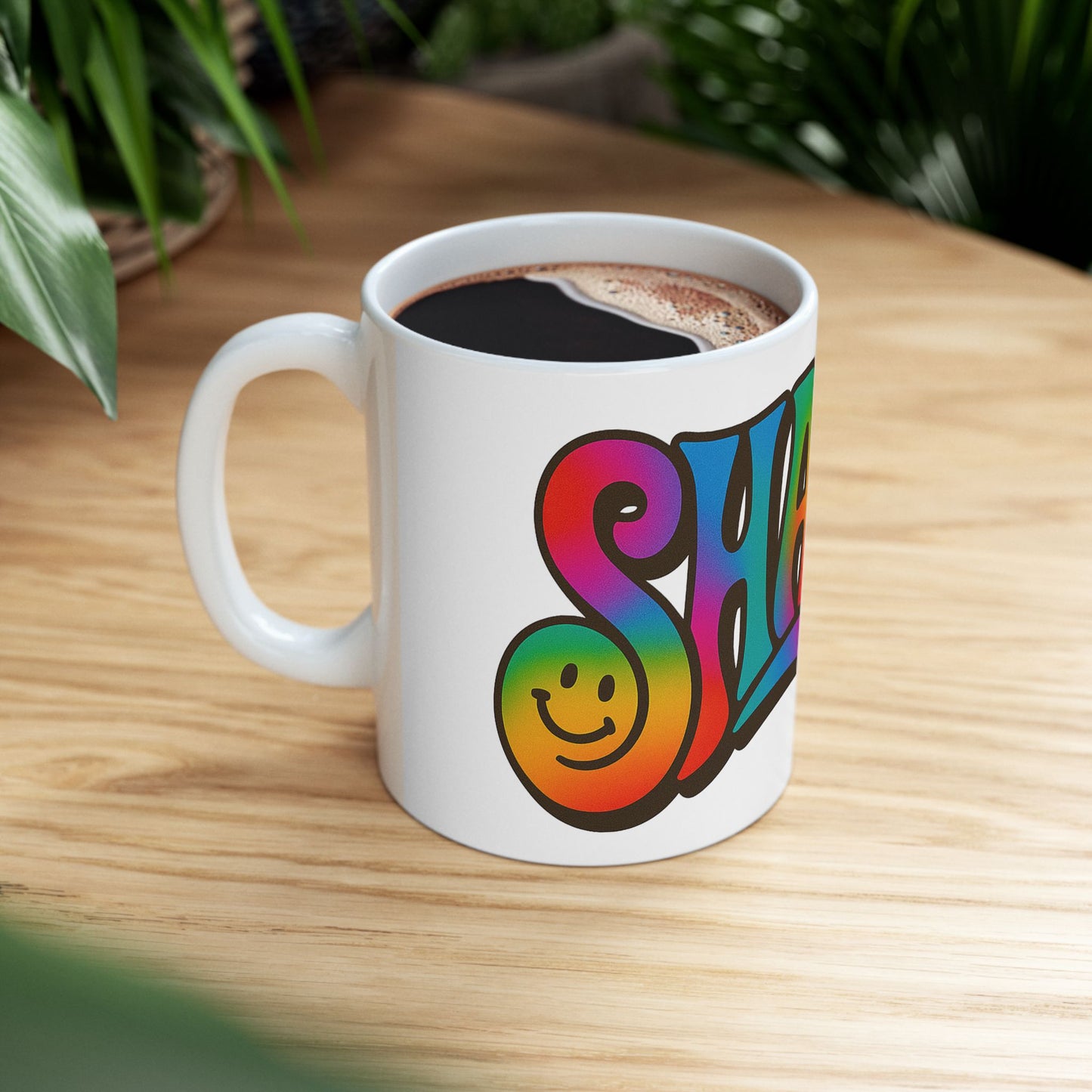 White mug with colorful 'Shalom' design on a wooden table