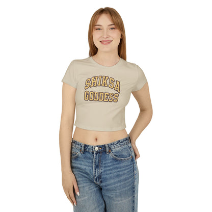 Woman wearing a beige t-shirt with 'SHIKSA GODDESS' text and blue jeans on a white background