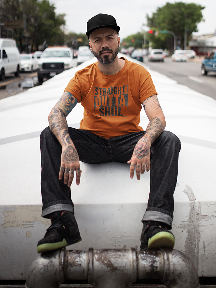 Man sitting on a vehicle's exhaust pipe with a city street background