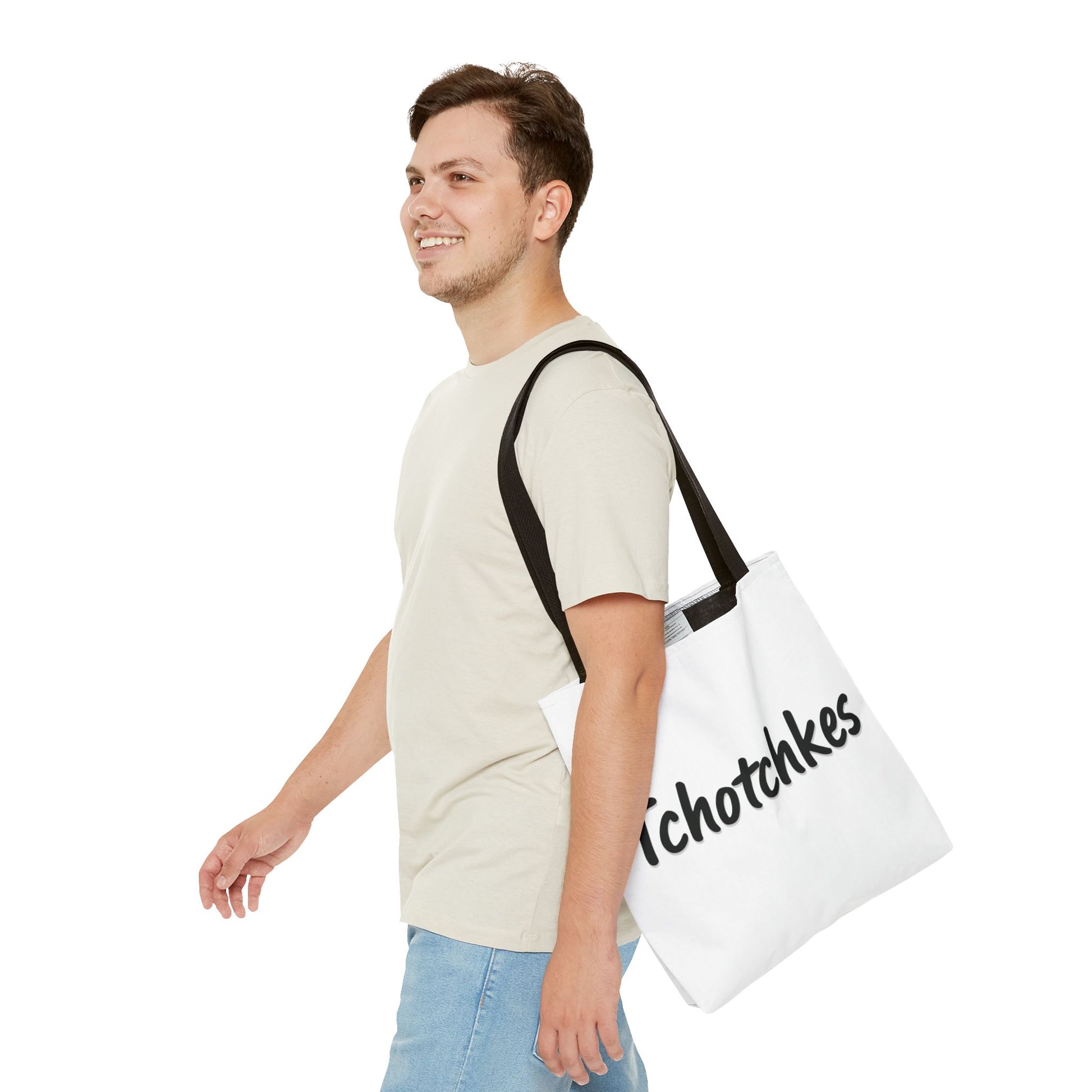 Man carrying a white tote bag with 'tchotchkies' text on a white background