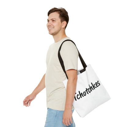 Man carrying a white tote bag with 'tchotchkies' text on a white background