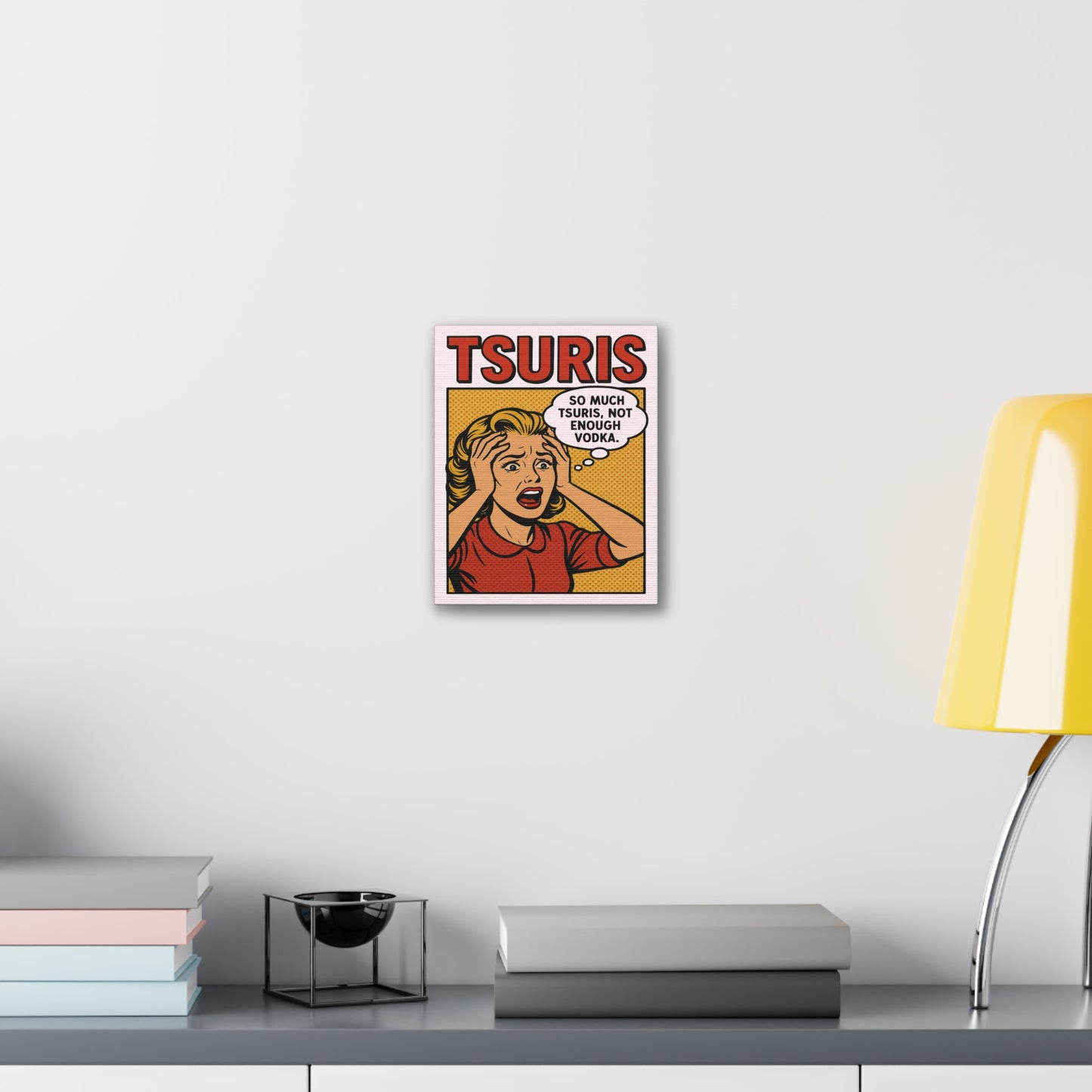 Framed poster with a comic-style design on a wall above a desk with books and a lamp.