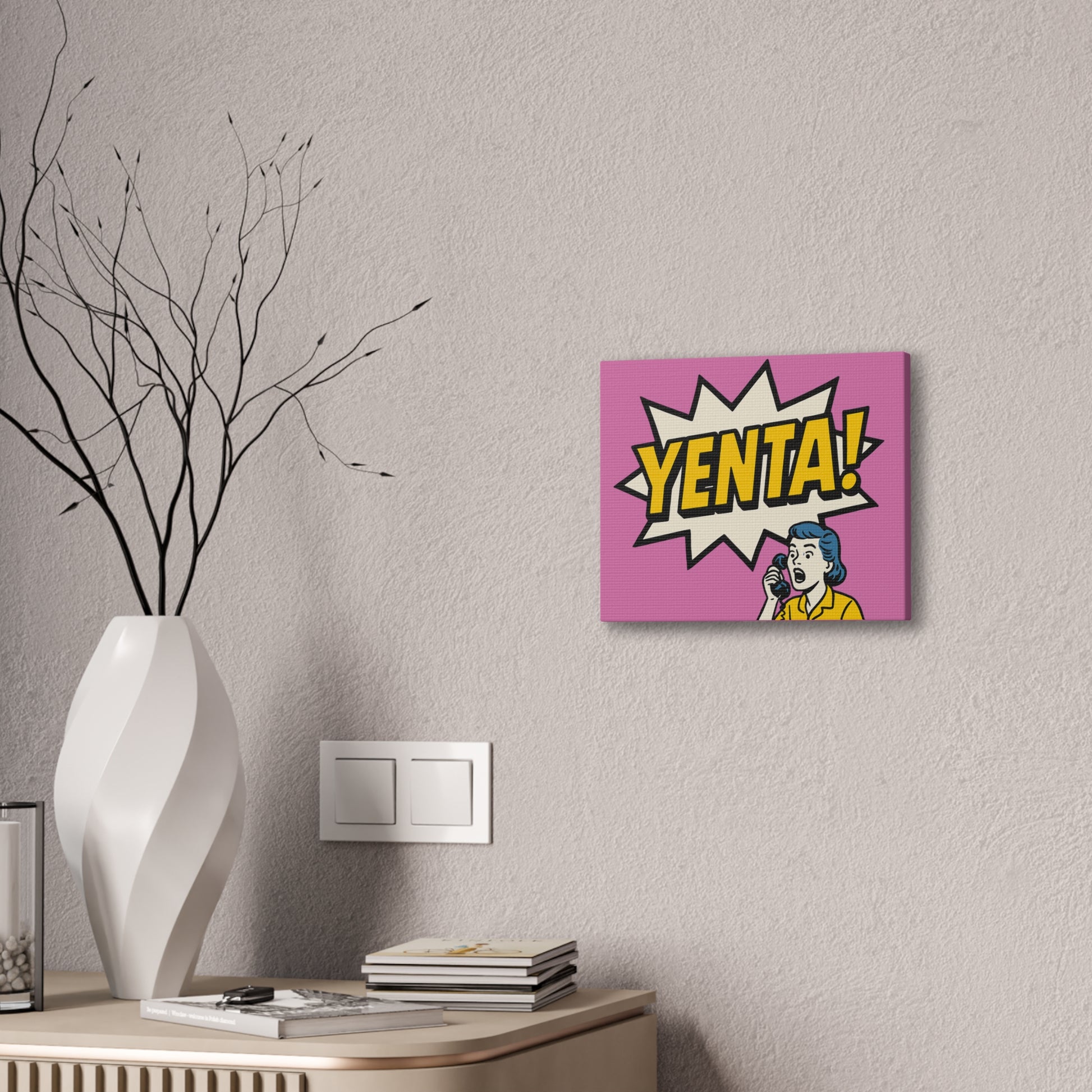 Canvas print with 'Yenta!' design on a wall above a desk with a vase and books.
