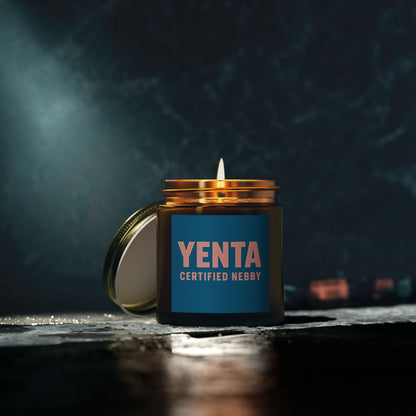 Candle in a jar labeled 'Yenta Certified Nebby' on a dark background