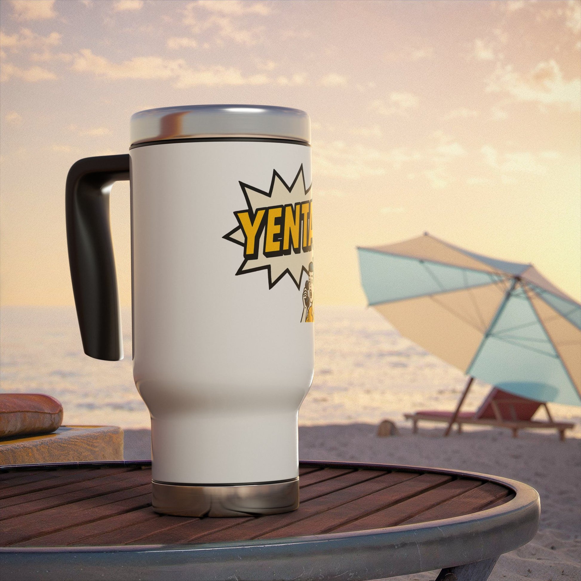 White travel mug with 'Yenta' logo on a beach table with an umbrella and sand in the background