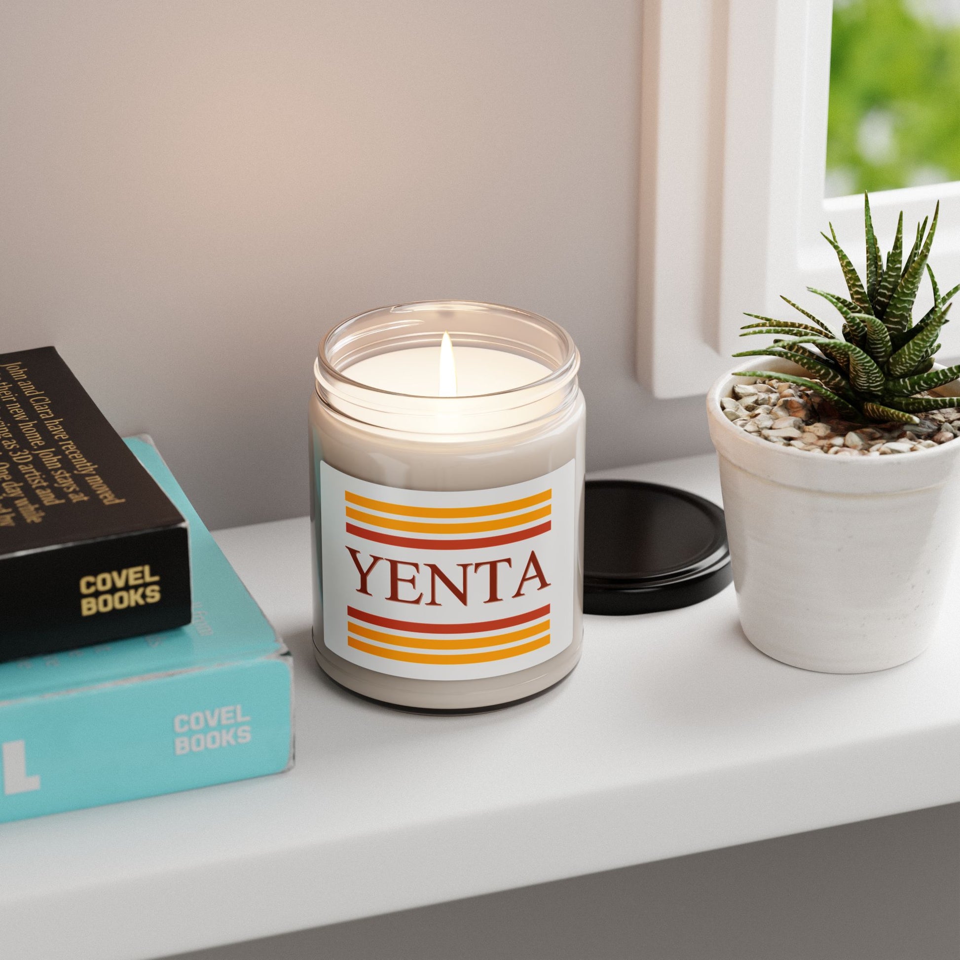 Yenta candle on a shelf with books and a plant