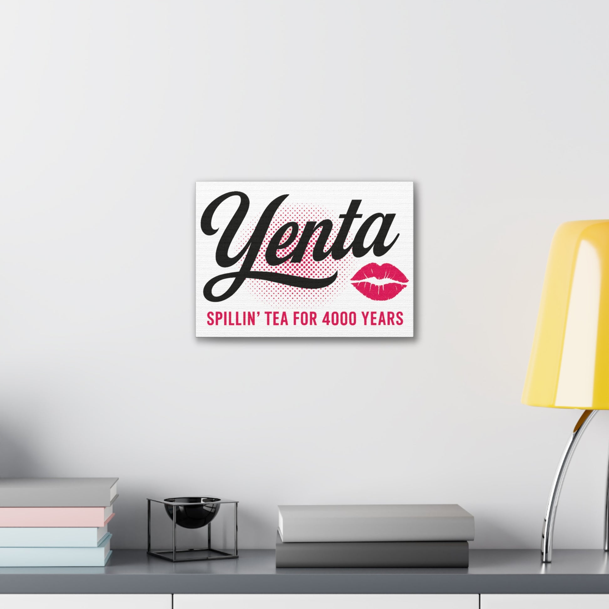 Framed artwork with 'Yenta' text and lip prints on a white wall above a desk.