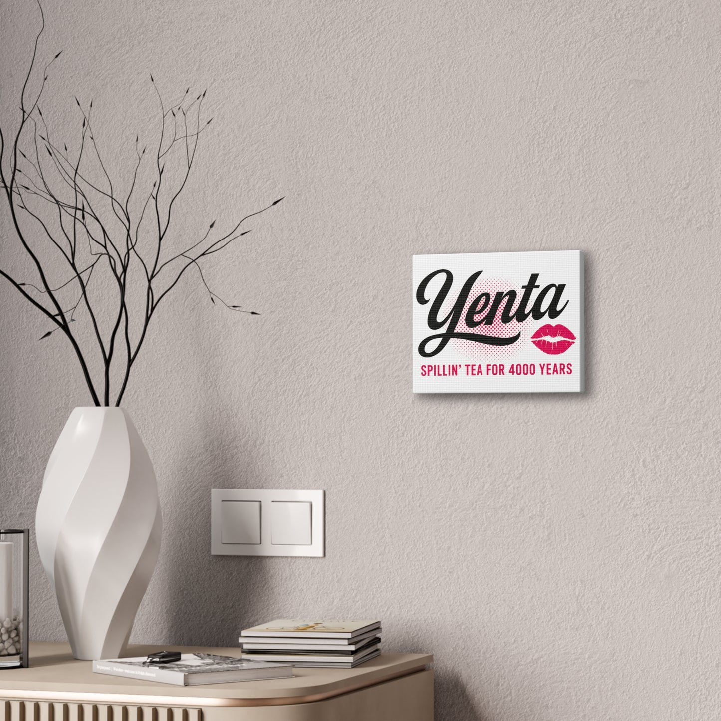 Decorative wall sign with 'Yenta' branding on a wall above a shelf with a vase and books.